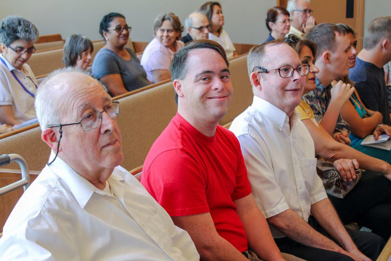 Group of people including several people with developmental disabilities sitting in pews at a church