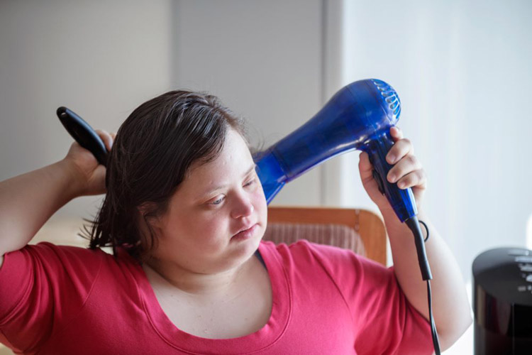 Woman with a developmental disability blowdrying her hair