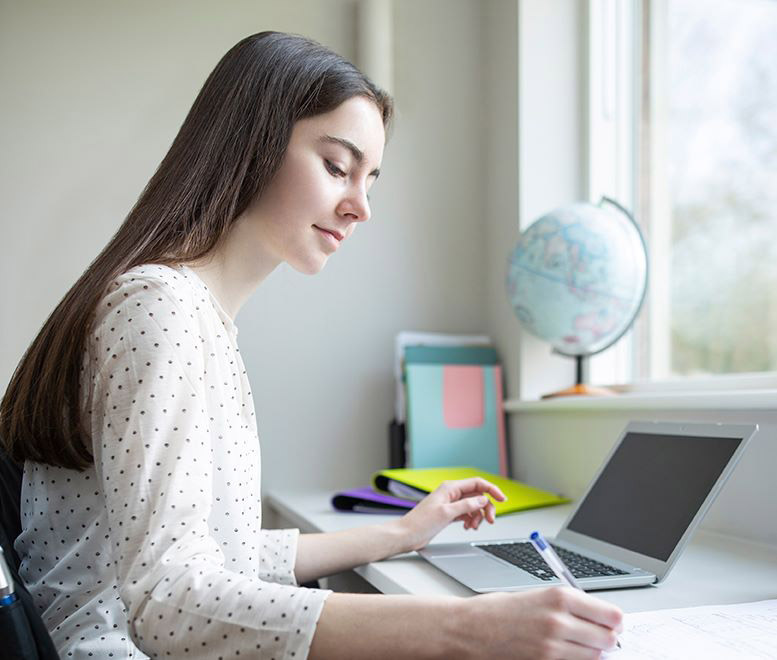 Young woman in front of a computer writing notes
