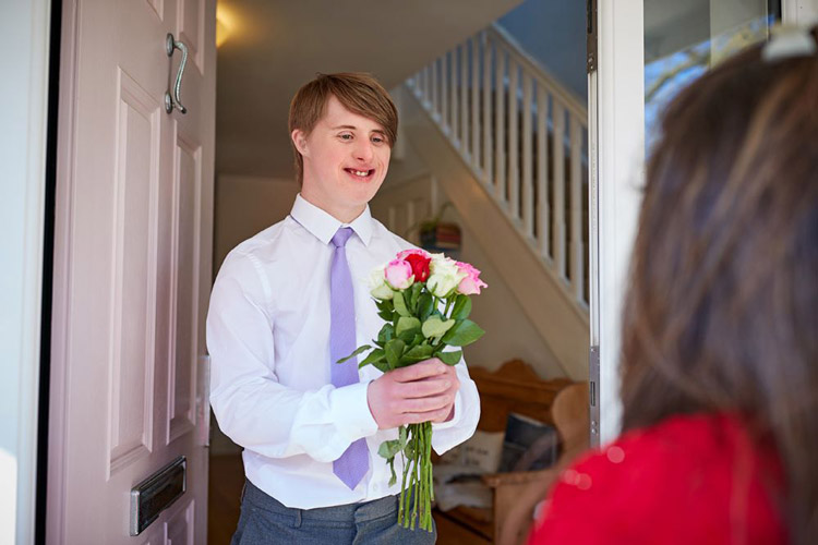 Man with a developmental disability dressed up and holding flowers