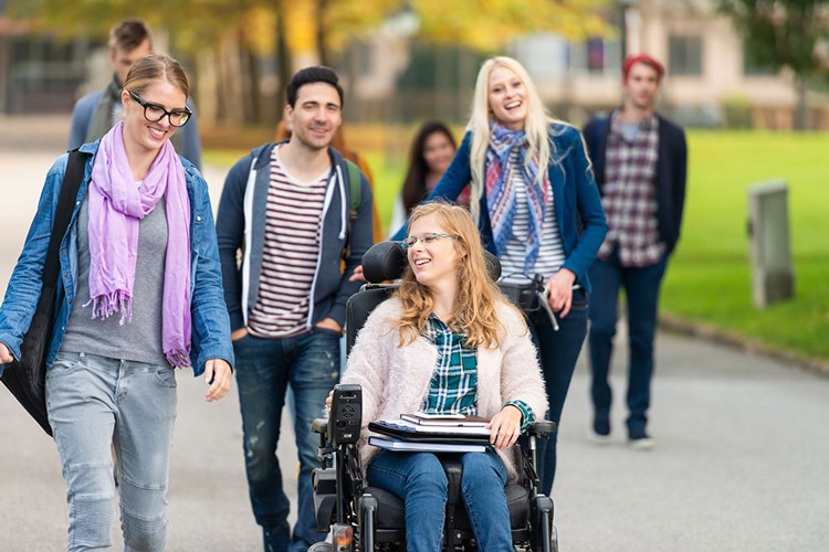 Woman in a wheelchair smiling with her classmates outdoors