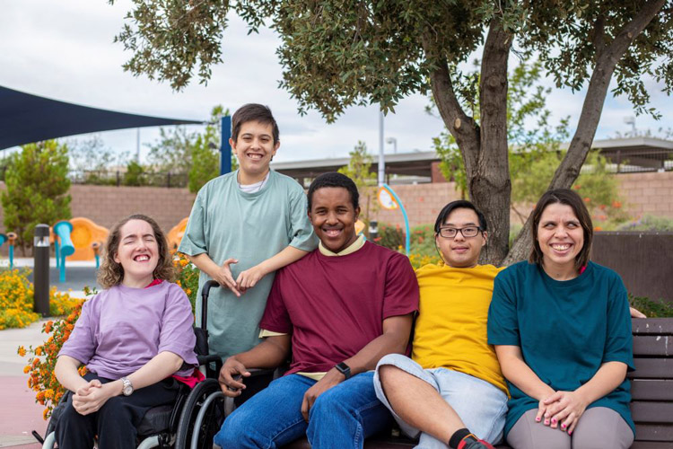 A group of people with developmental disabilities smiling at a park