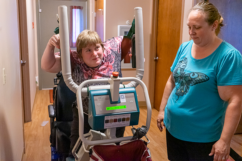 Woman with a disability using a machine with her caregiver watching
