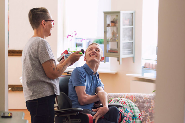 Man with IDD in a wheelchair smiling with his mother