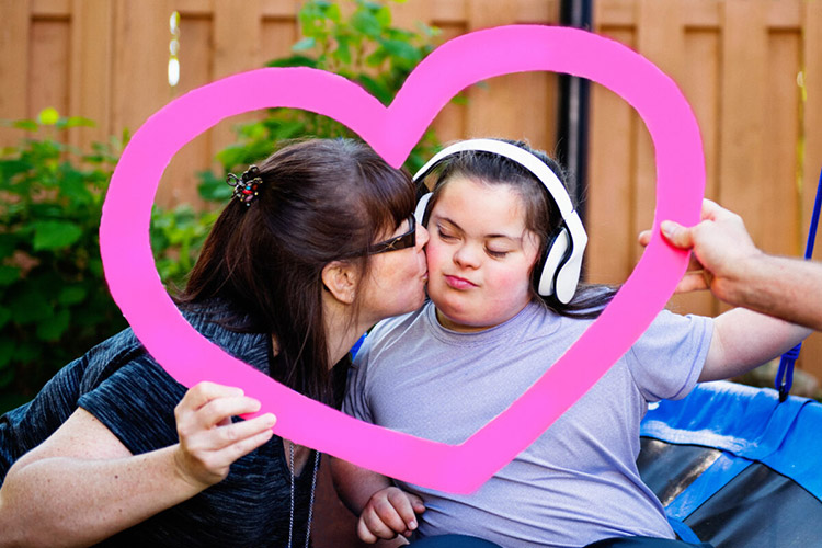 Woman with a younger woman with IDD holding a pink heart cutout