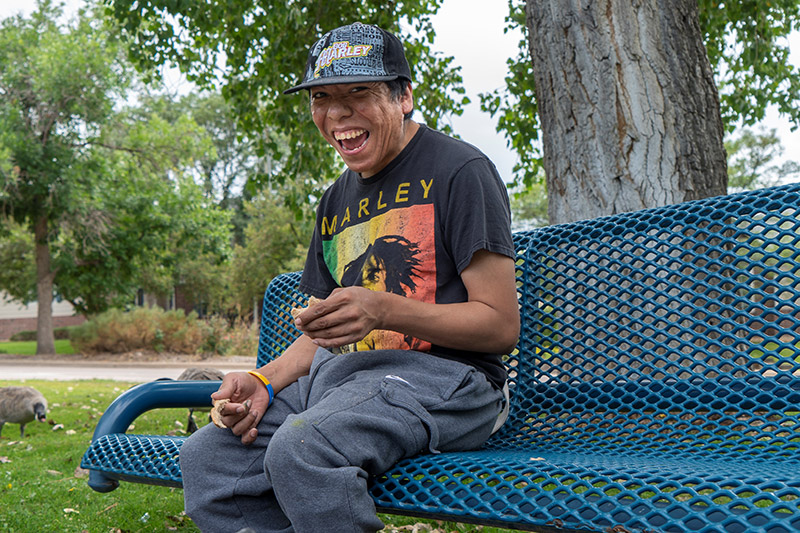 Daven, a man with a developmental disability, smiling on a park bench