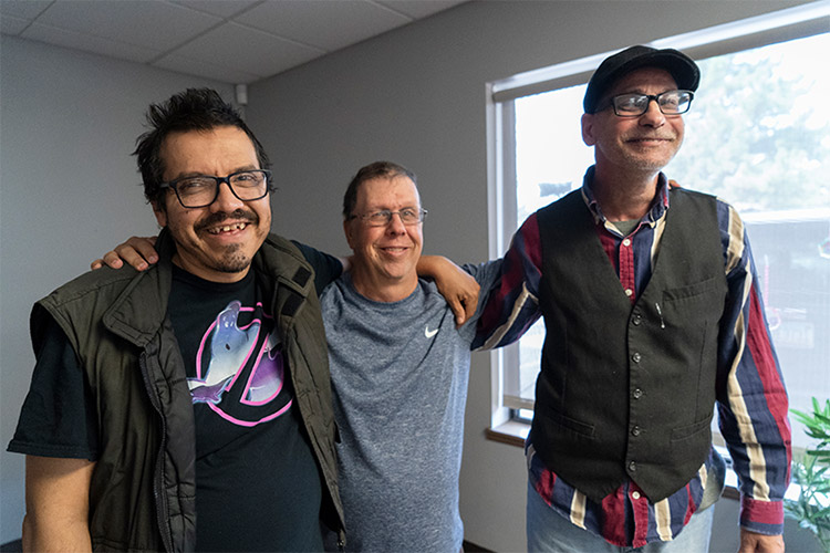 Group of three men with IDD posing and smiling