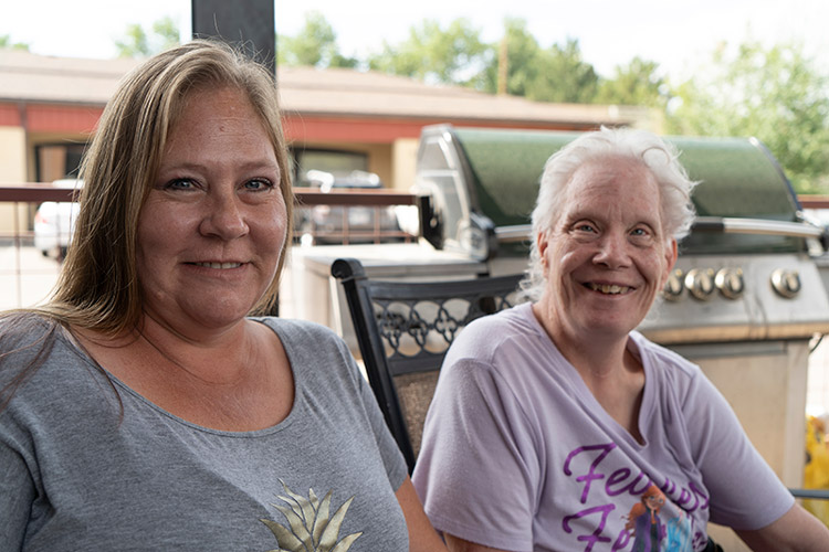 Female caregiver smiling with an older woman with a developmental disability