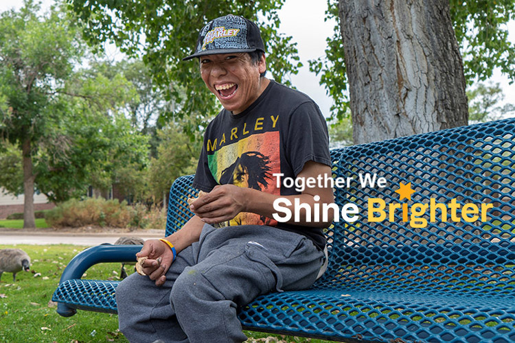 Smiling person with a developmental disability sitting on a park bench