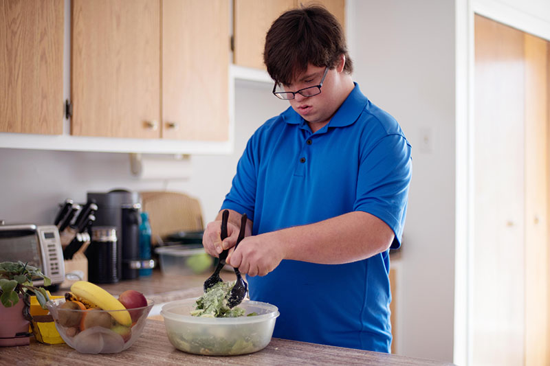 Young man with Down Syndrome learning cooking