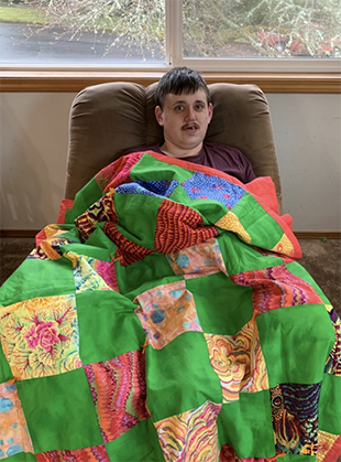 Ben Fuerstenau snuggled under gift quilt for camp family