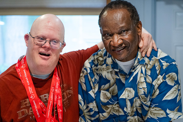 Man wearing medals from a Special Olympics event celebrates with an AbleLight DSP