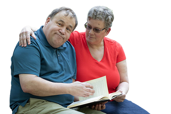 Cutout of a man with IDD reading a book with his caregiver