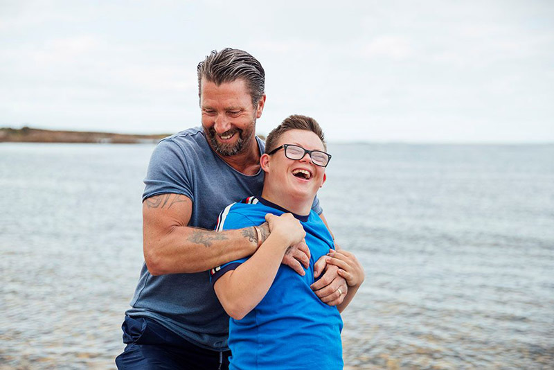 Father hugging his son with a developmental disability on a beach