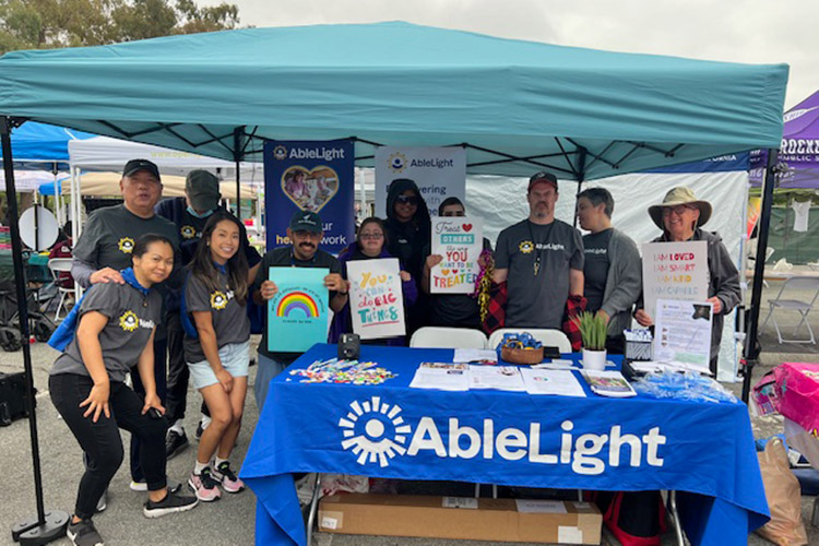 Group of AbleLight team members and people supported by AbleLight outside at an event