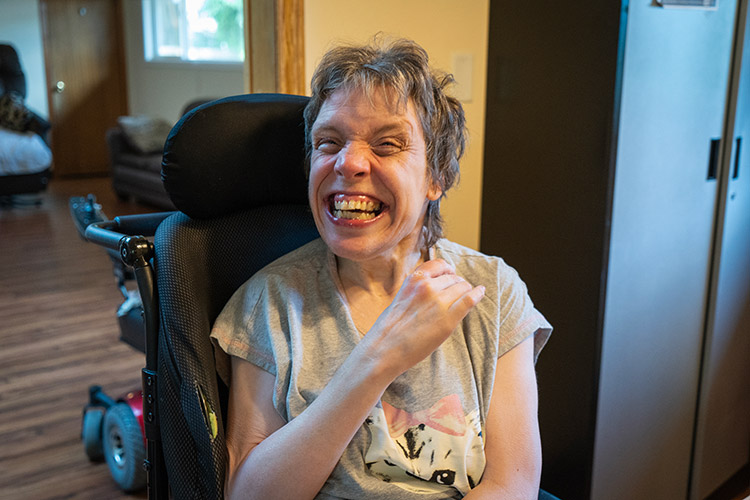 Woman in a wheelchair smiling in an AbleLight home