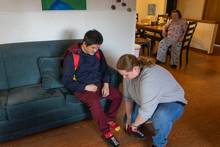 An AbleLight DSP helping a man with a developmental disability put his shoes on