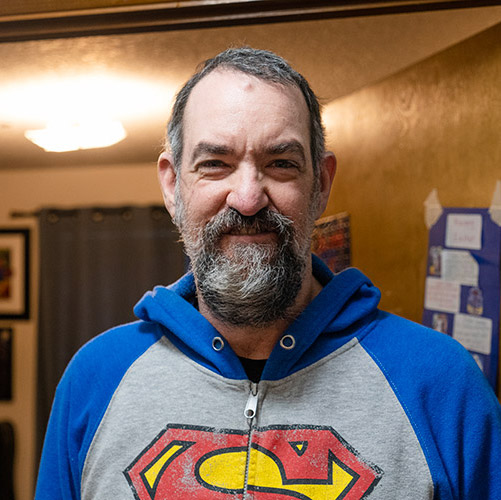 Man with a developmental disability smiling in front of his room in an AbleLight home