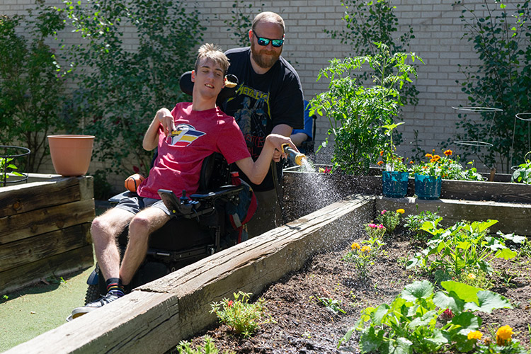 Trevor and James watering flowers at an AbleLight Day Program