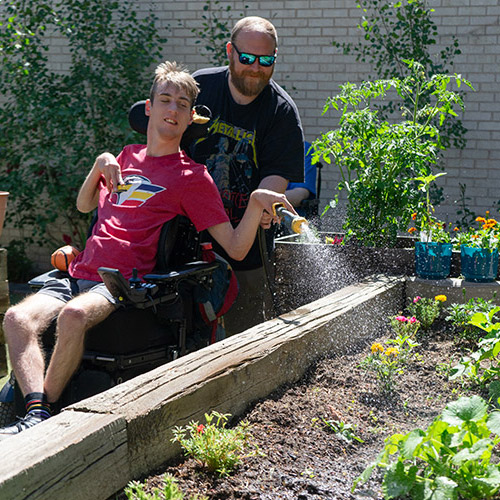 Man with a developmental disability watering plants in a garden