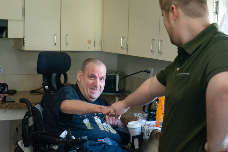 Michael, a man with a developmental disability in a wheelchair, making coffee with a DSP