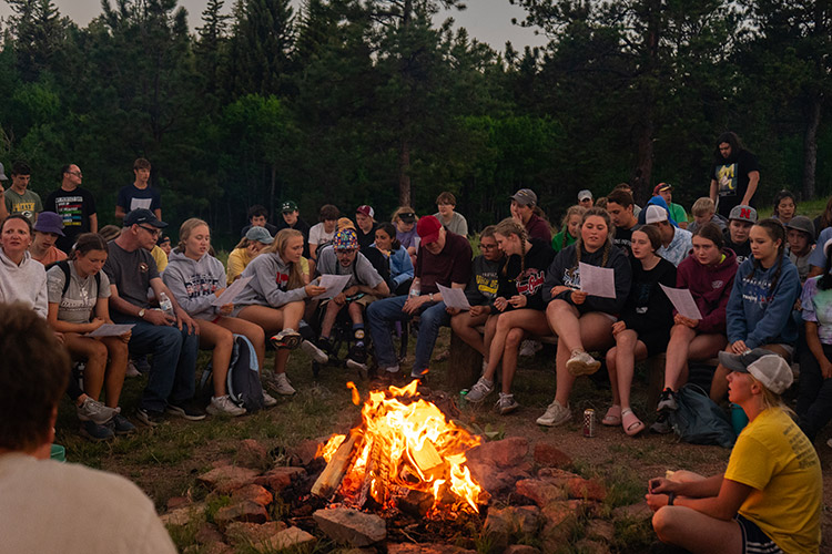 Group of campers singing worship songs around a campfire