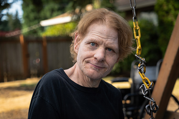 Man with a developmental disability standing by a park swing