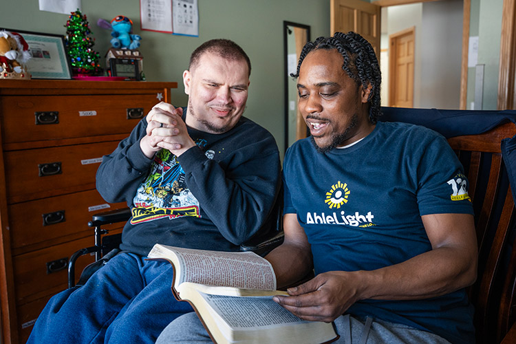 An AbleLight DSP and a man with a developmental disability reading a bible together