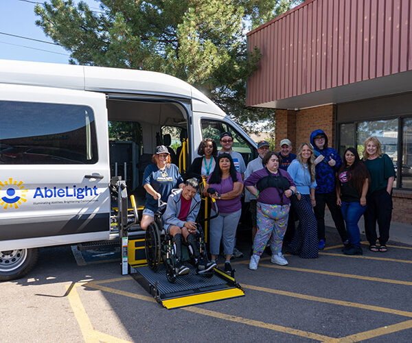 Group of AbleLight team members and people with developmental disabilities in front of an AbleLight van