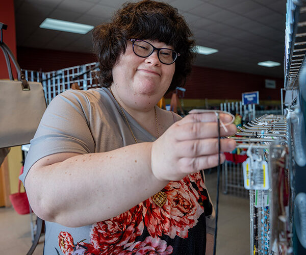 Nicole placing jewelry on a hook at an AbleLight Thrift Shop