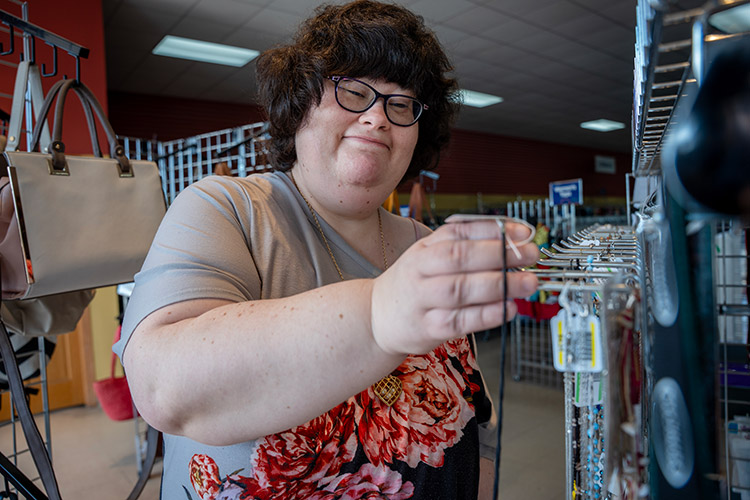 Nicole placing jewelry on a hook at an AbleLight Thrift Shop