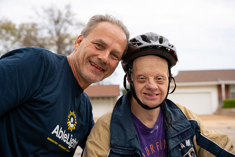 An AbleLight DSP smiling with a man with developmental disabilities outside