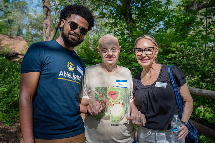 An AbleLight employee, a man with a IDD and an AbleLight Board Member posing