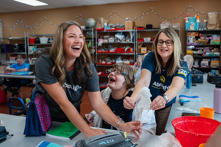 A participant at AbleLight's Fort Collins Day Program with two team members
