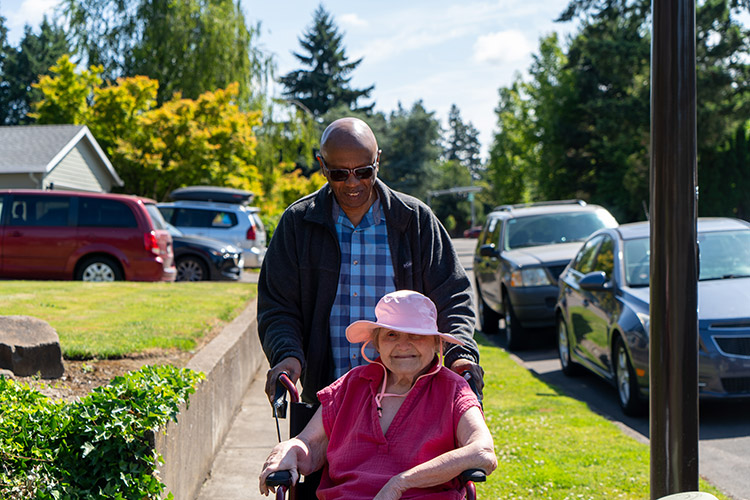 An AbleLight team member pushing a woman with IDD in a wheelchair