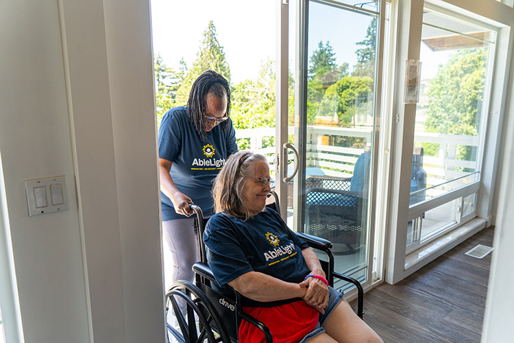 An AbleLight employee pushing the wheelchair of a woman supported by AbleLight