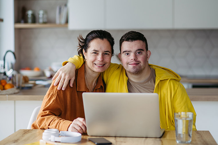 A man with IDD and a woman with a laptop in the kitchen