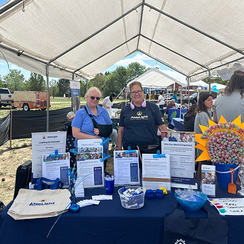 Two women at an AbleLight informational table outside