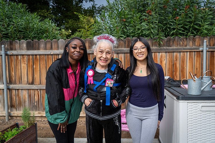 Two AbleLight team members smiling with a woman supported by AbleLight