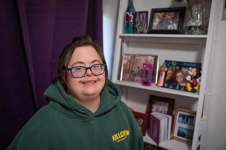 A woman with a developmental disability smiling in her decorated room