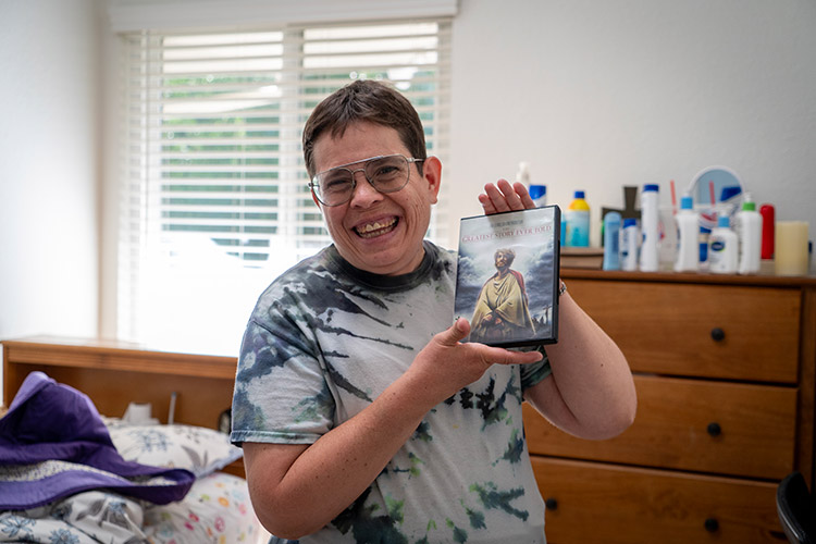 A woman supported by AbleLight smiling and holding a religious movie